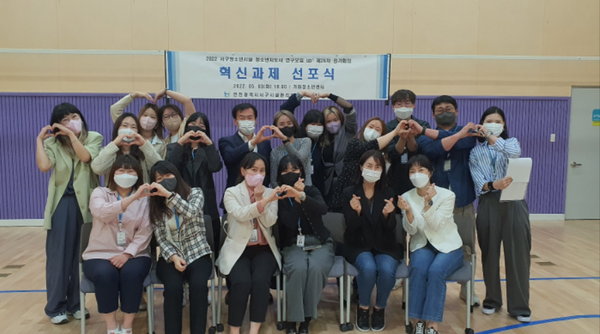        ▲사진 = 뒷줄 가운데 구재용 이사장이 옆에직원과 손으로 하트표시를 하고 있다.